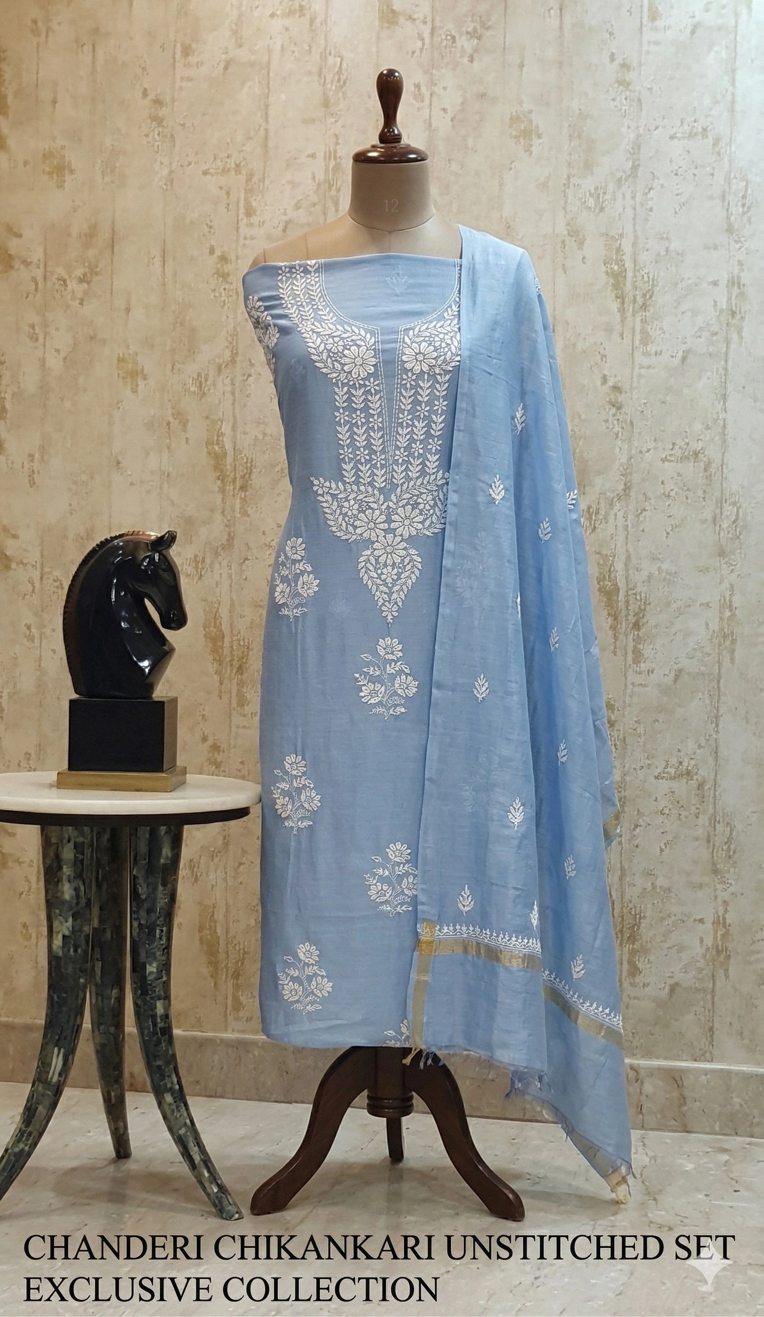 Light blue embroidered saree on a mannequin against a beige wall.