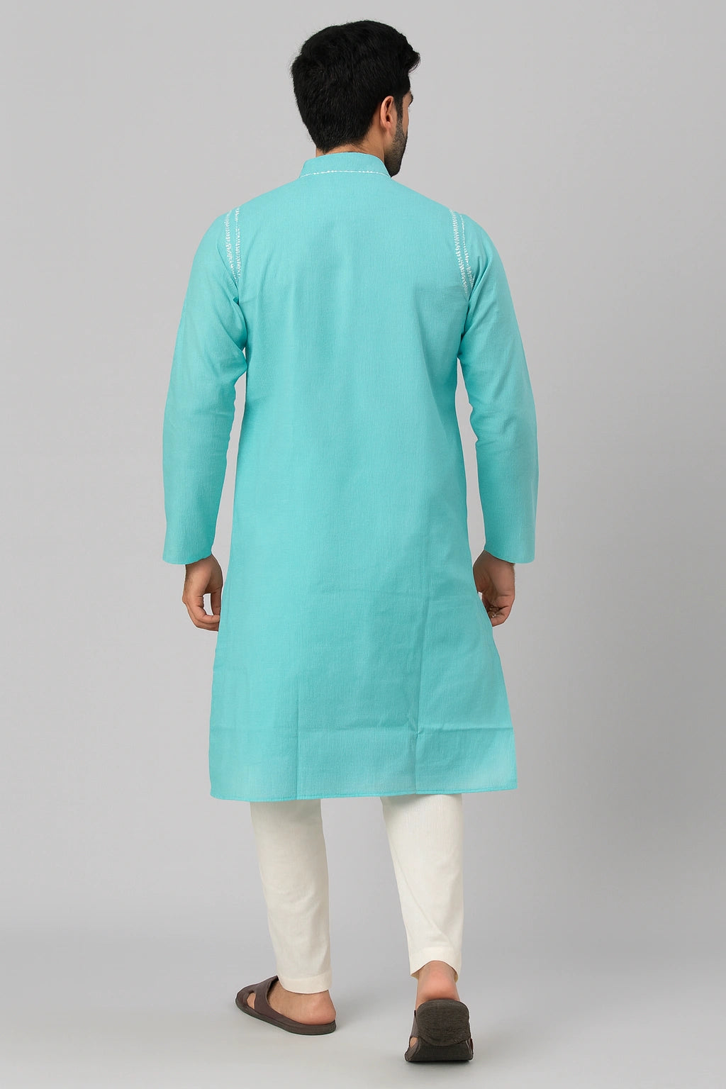 Man wearing a lucknowi chikankari turquoise kurta with white pants on a gray background