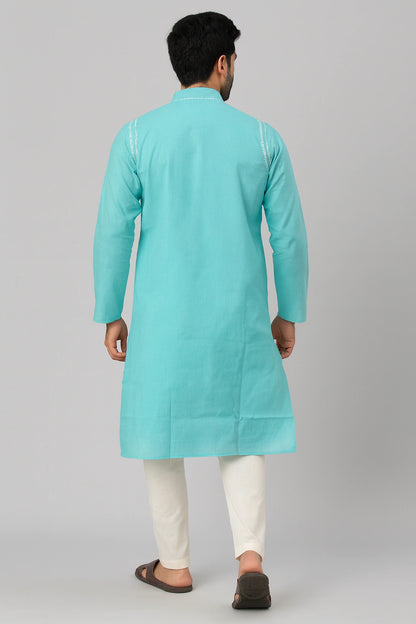 Man wearing a lucknowi chikankari turquoise kurta with white pants on a gray background
