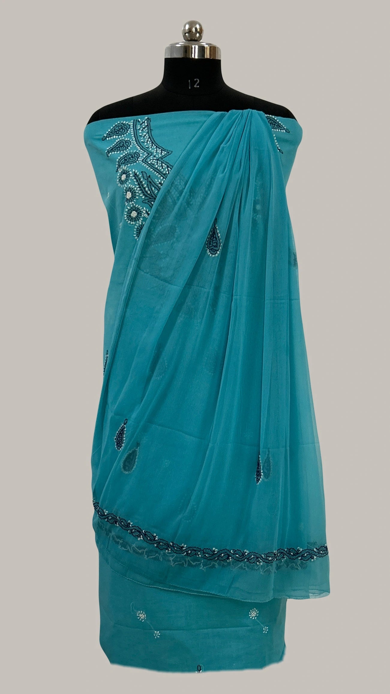 Lucknowi Chikankari Teal saree with decorative patterns on a mannequin against a gray background