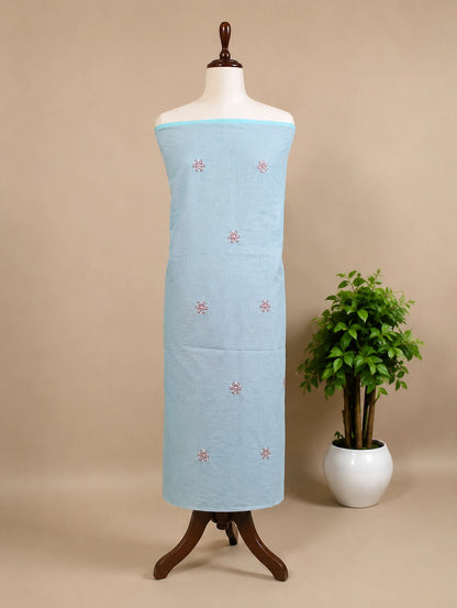 Lucknowi Chikankari Light blue fabric with red patterns on a mannequin against a beige background with a plant.