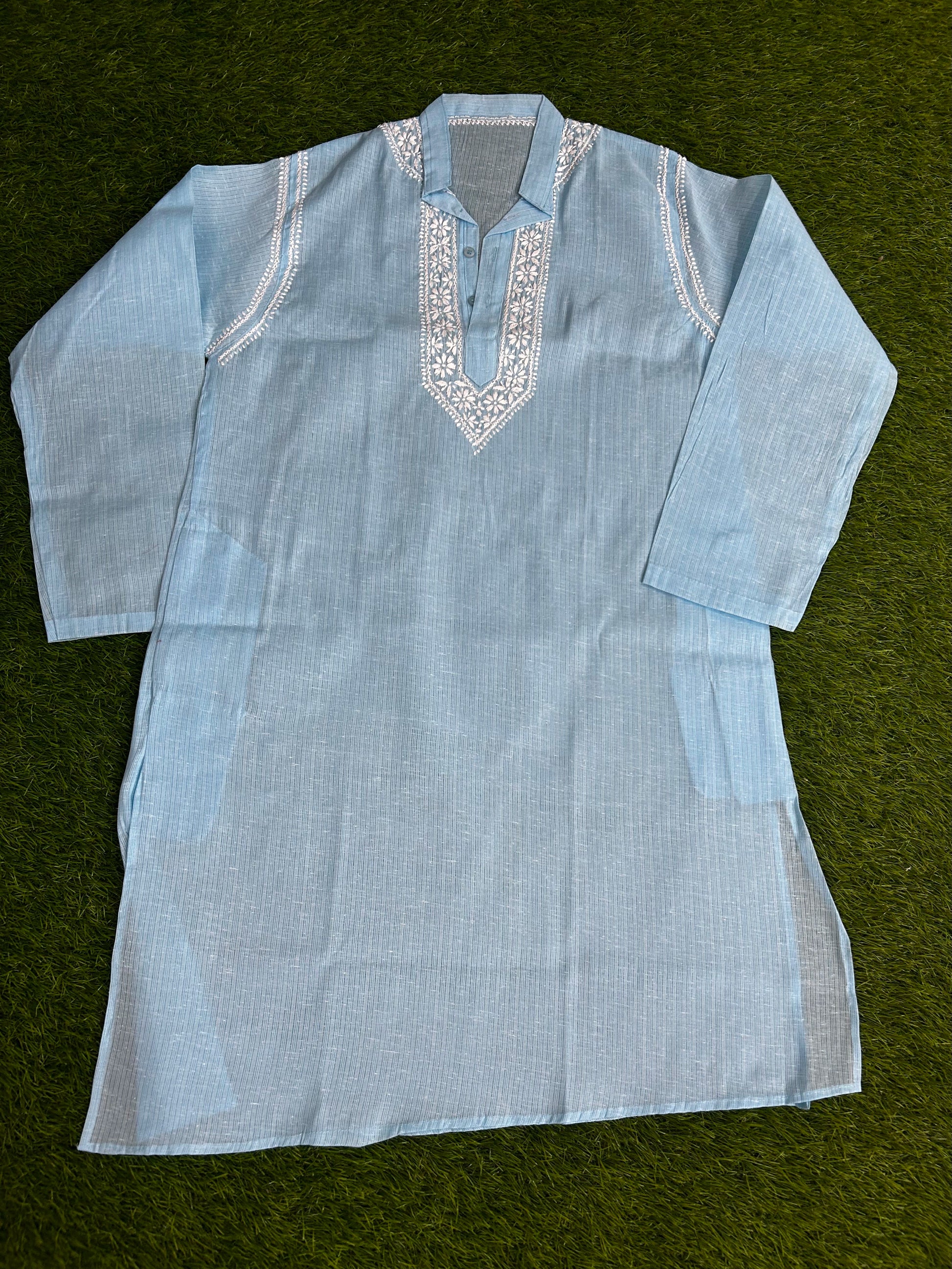 Light blue embroidered shirt on a green background
