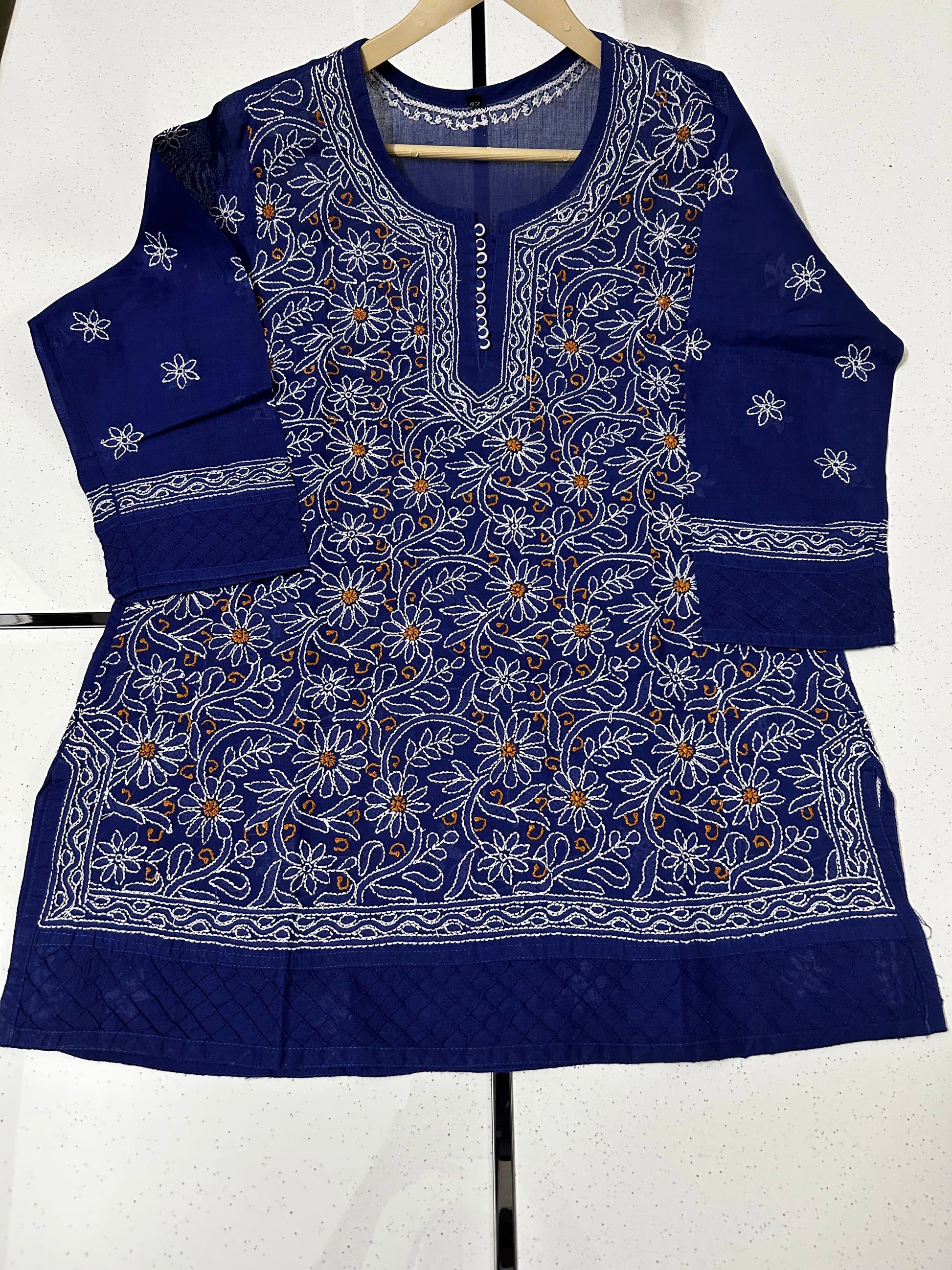 Blue embroidered traditional outfit on a hanger against a white background