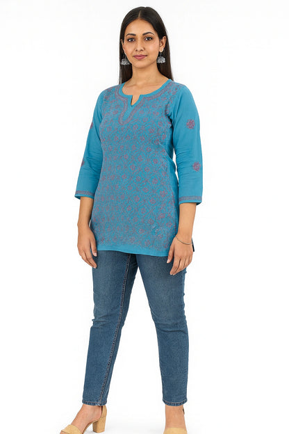 Woman wearing a lucknowi chikankari blue patterned top and jeans on a white background