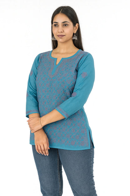 Woman wearing a lucknowi chikankari blue patterned top and jeans on a white background