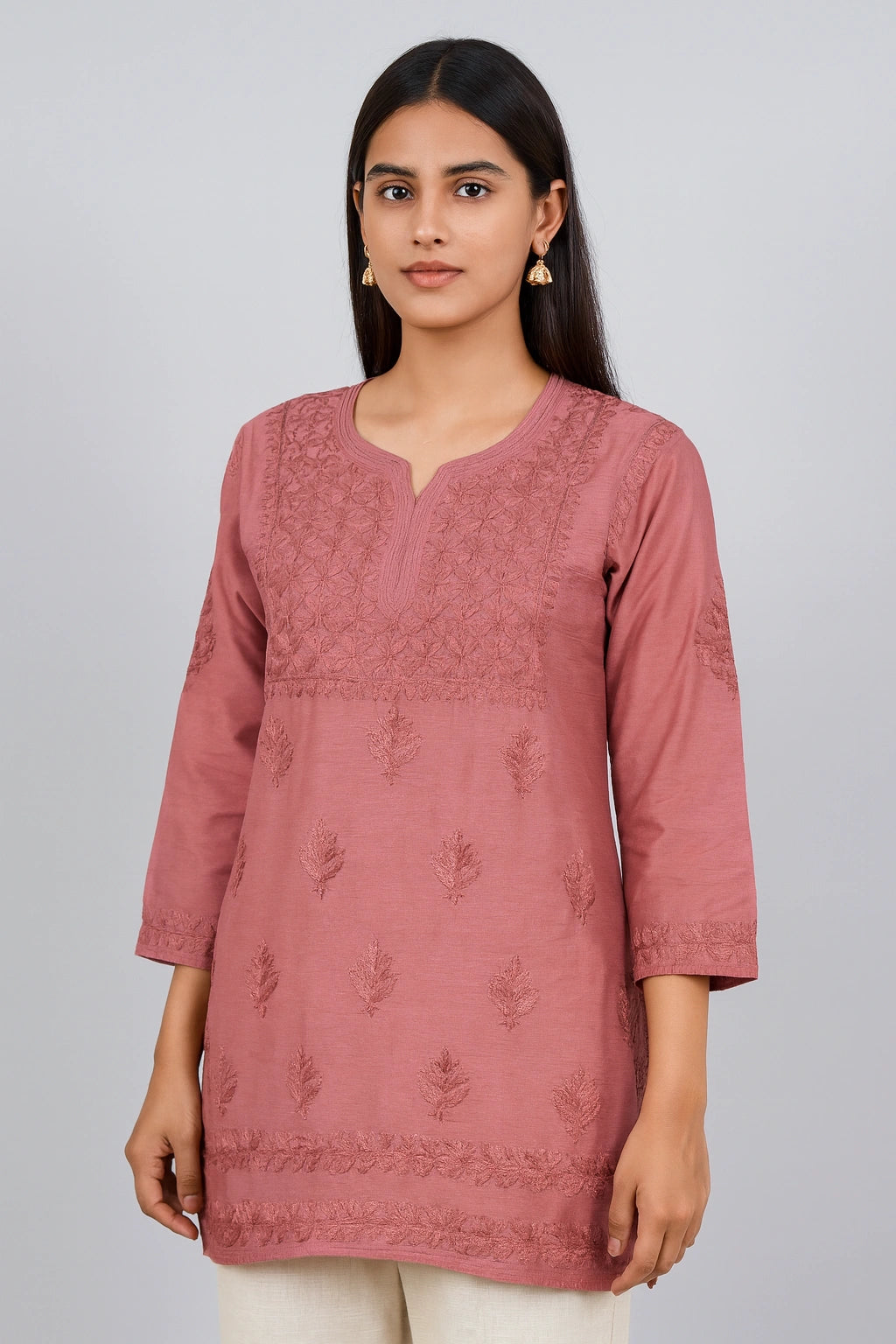 Woman wearing a pink embroidered kurta against a plain background