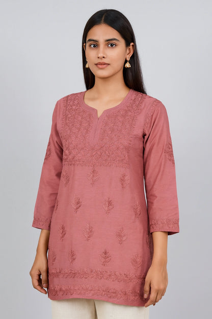 Woman wearing a pink embroidered kurta against a plain background