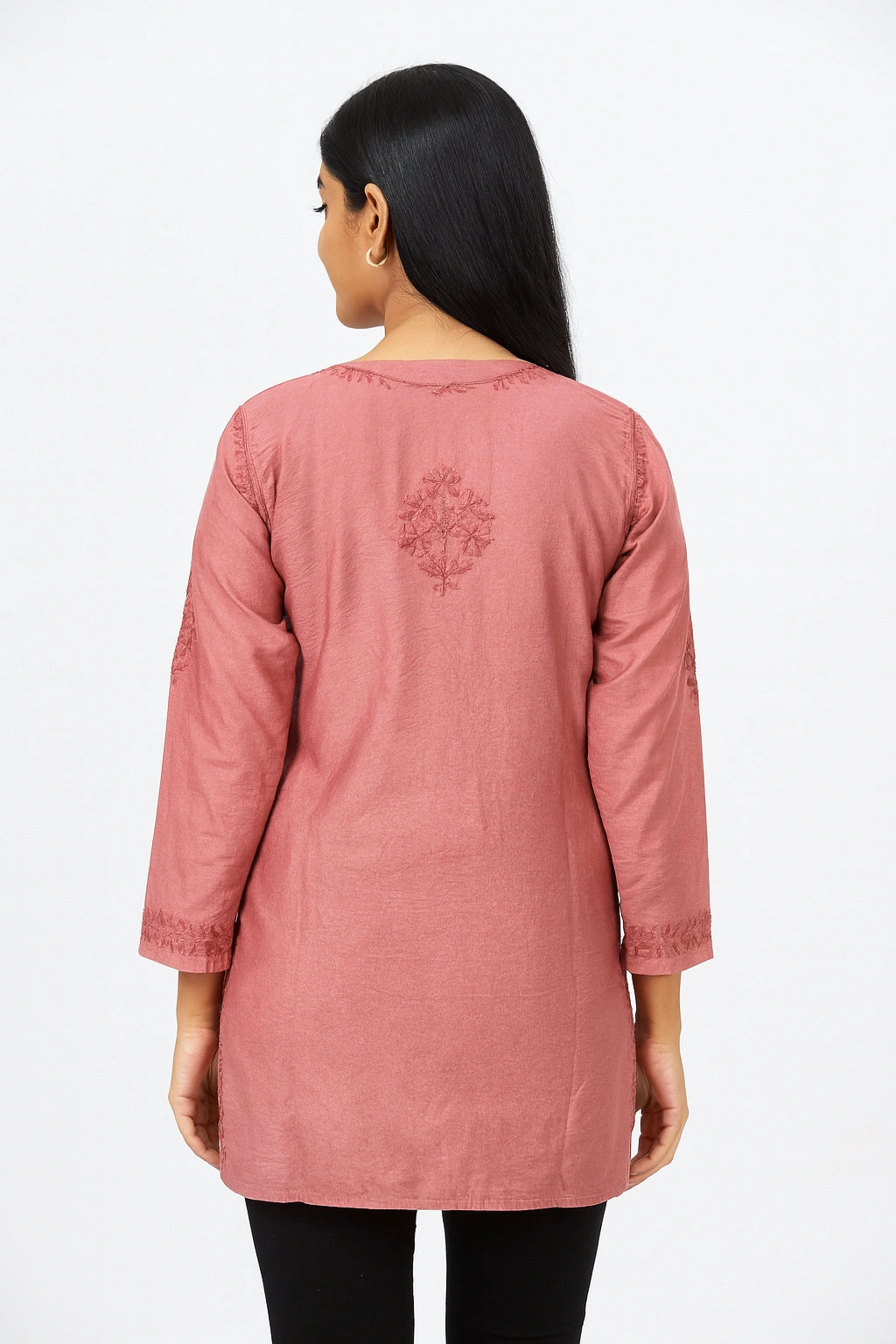 Woman wearing a pink embroidered top on a white background
