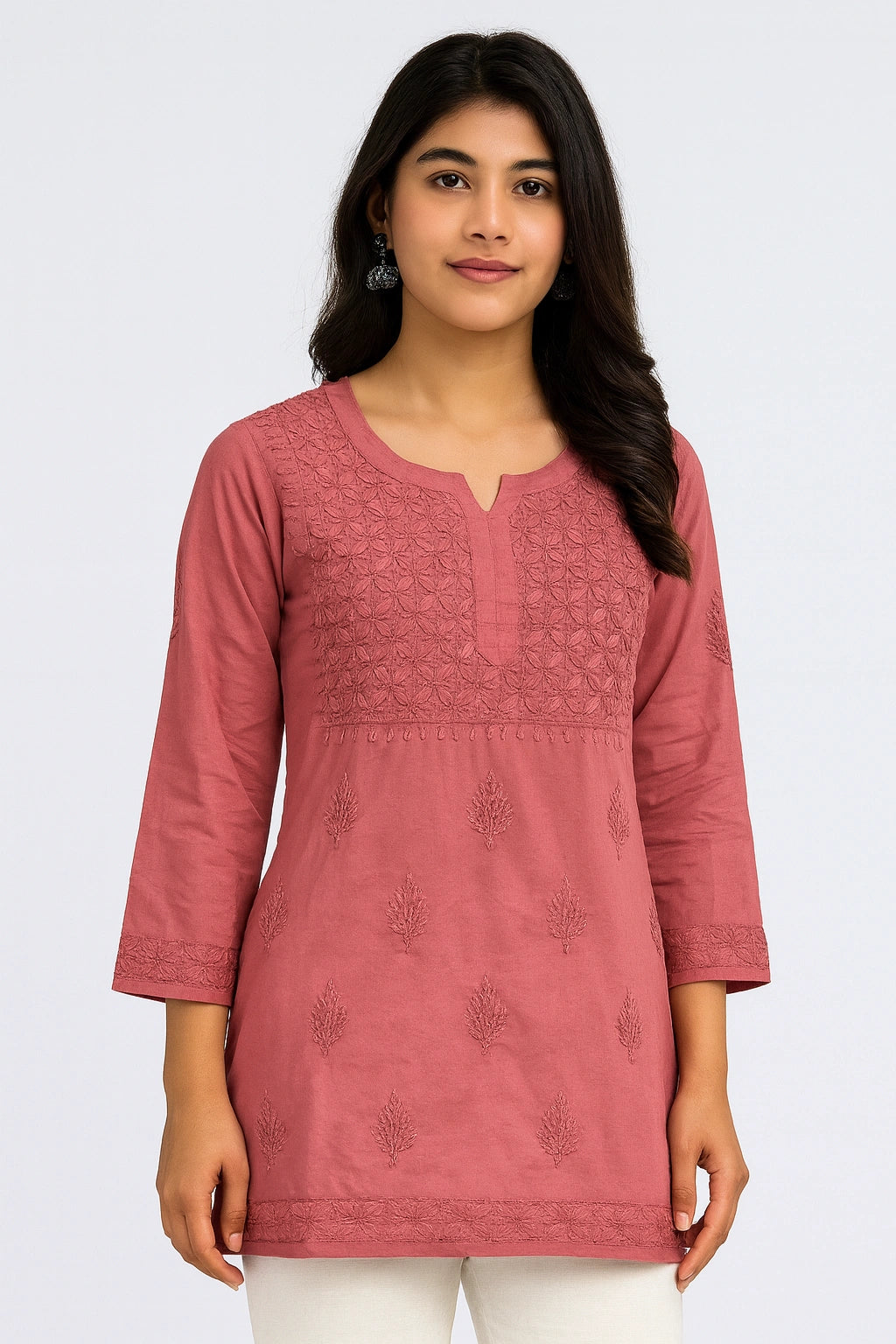 Woman wearing a pink embroidered kurta against a white background