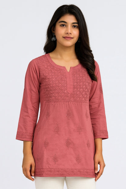 Woman wearing a pink embroidered kurta against a white background