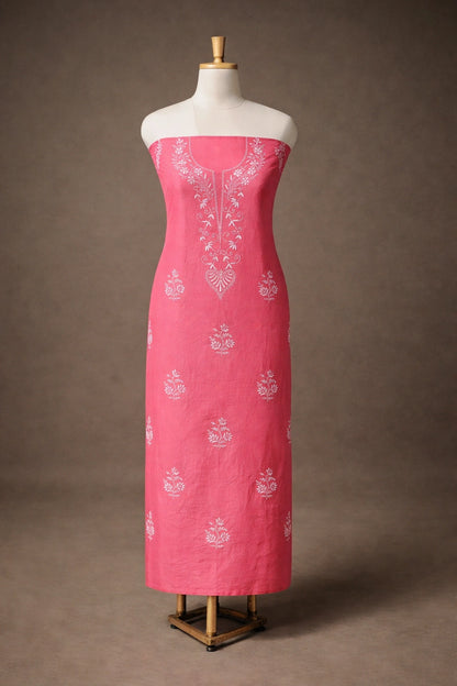 Pink dress with white embroidery on a mannequin against a brown background