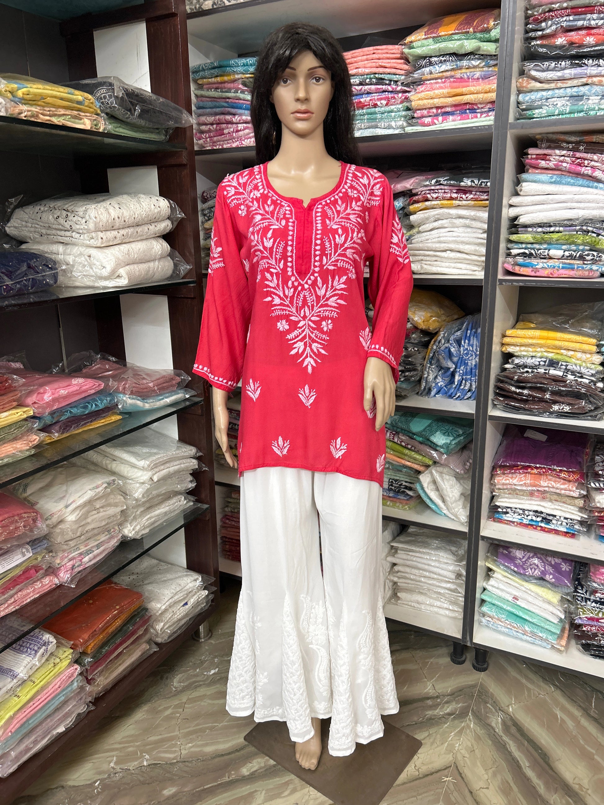 Mannequin wearing a lucknowi chikankari red and white outfit in a fabric store