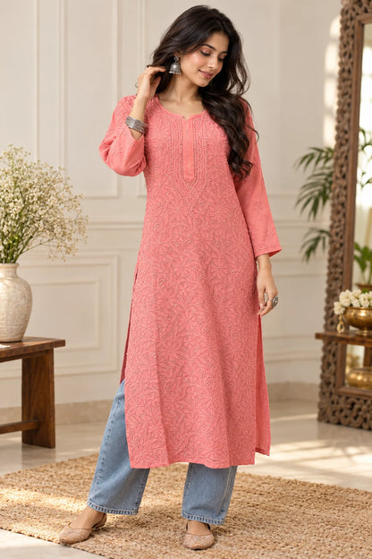Woman wearing a lucknowi chikankari coral pink-colored kurta with white floral patterns 