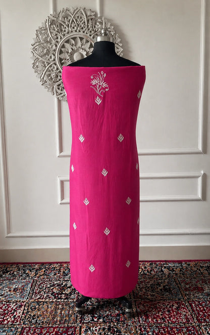 lucknowi chikankari Pink dress with white patterns on a mannequin against a decorative wall.