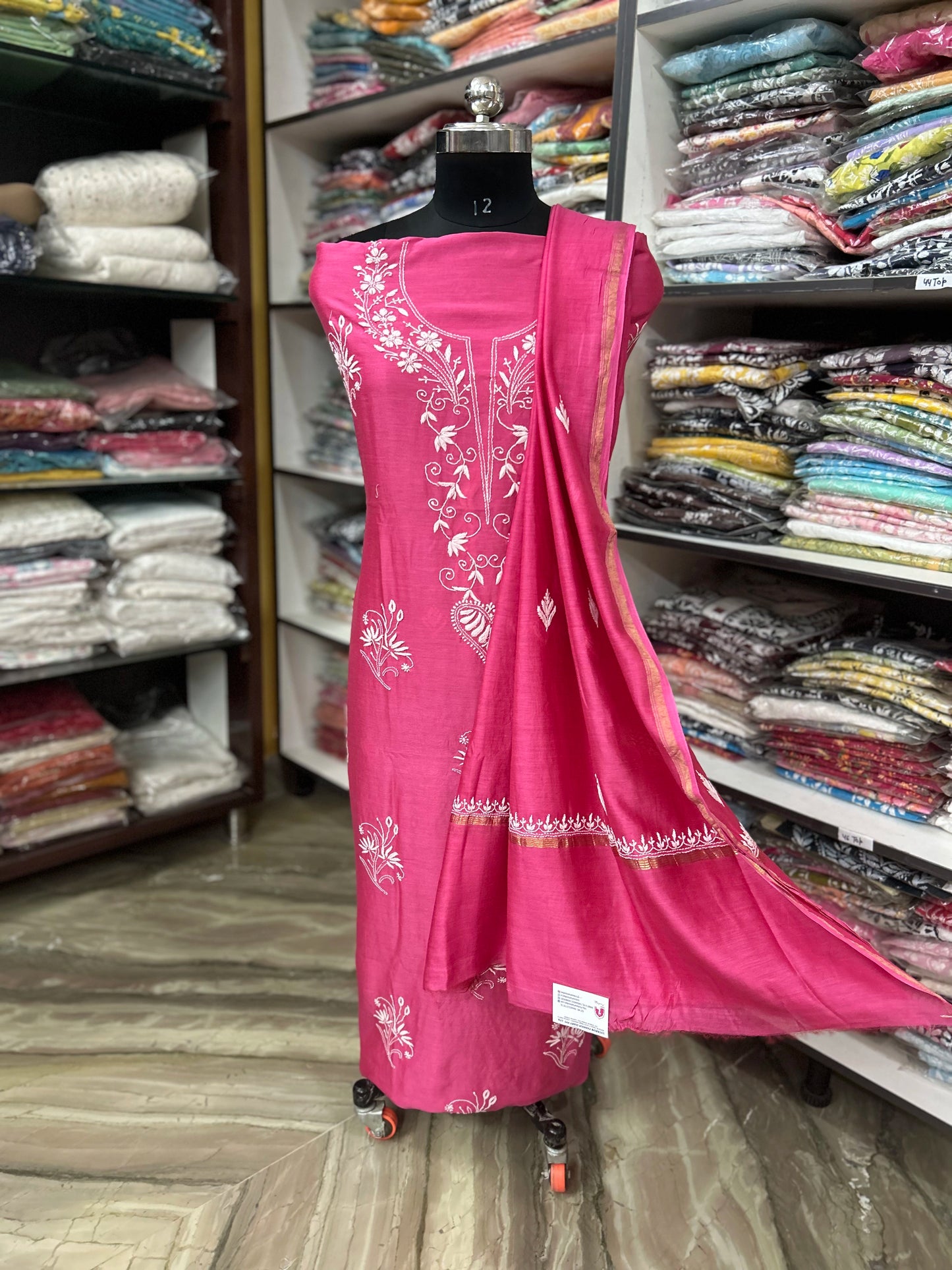 Pink embroidered dress on a mannequin in a fabric store