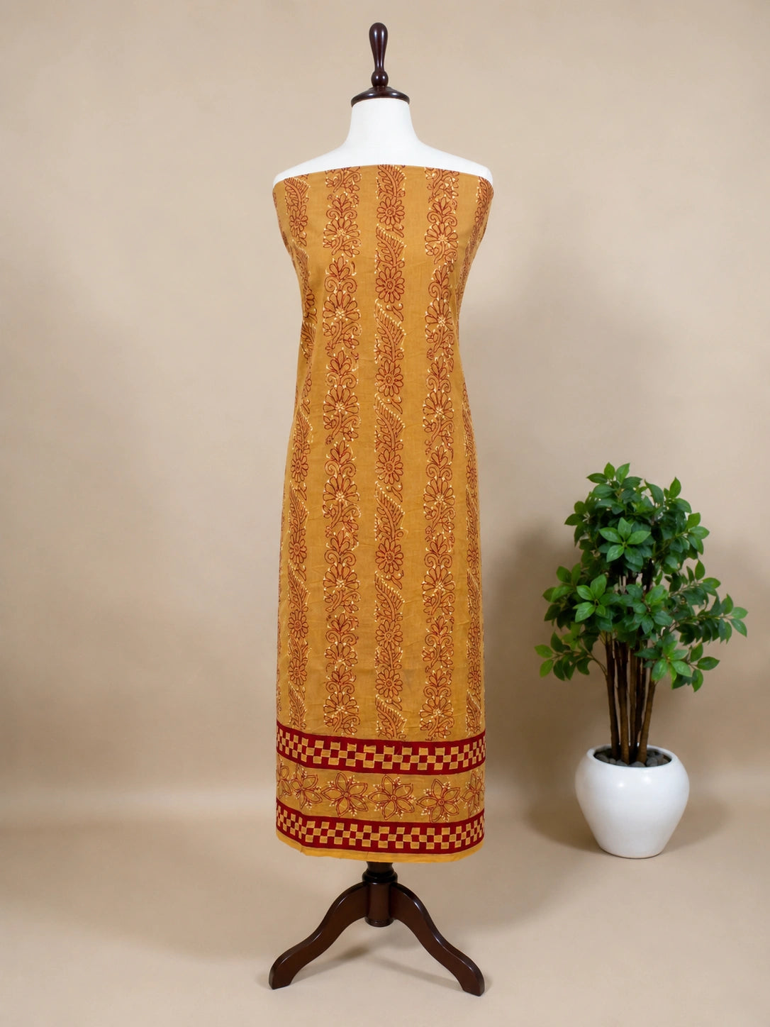 Lucknowi Chikankari Yellow patterned dress on a mannequin with a plant on a beige background