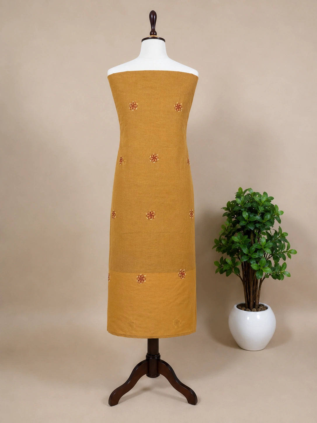 Lucknowi chikankari Mustard yellow dress on a mannequin with a plant in the background