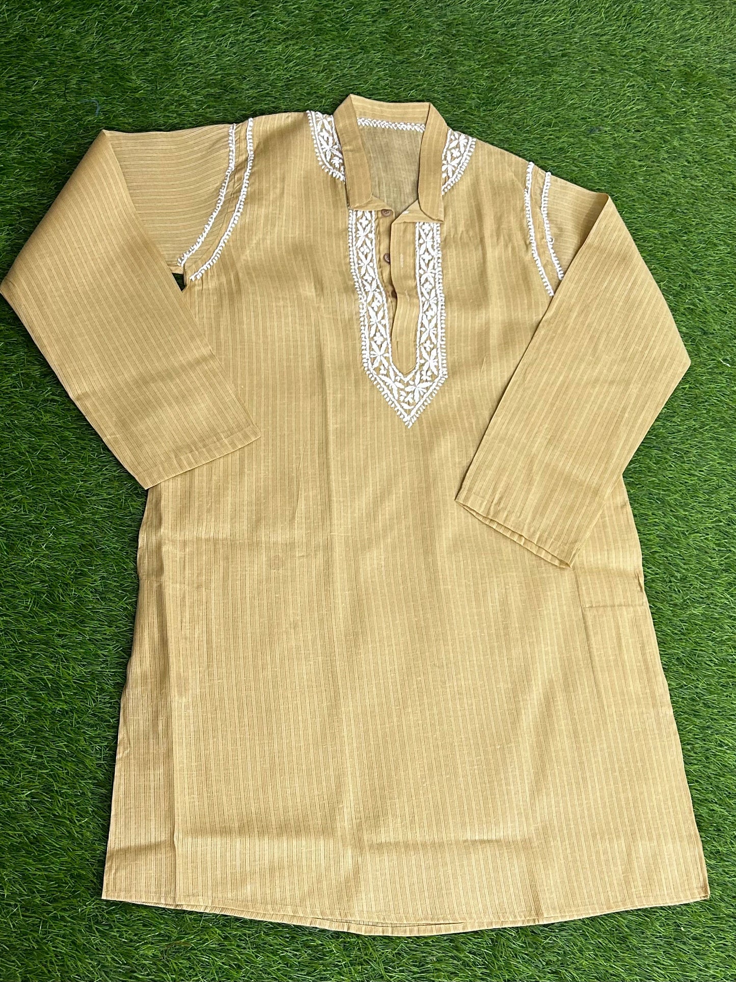 Beige kurta with white embroidery on a green background