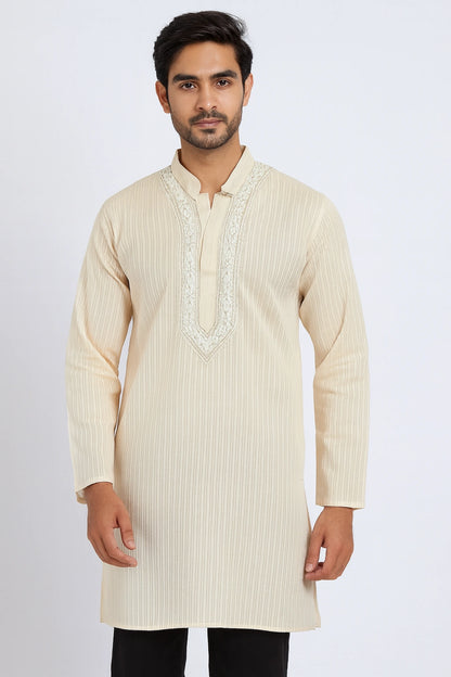 Man wearing a cream kurta with intricate embroidery on a white background