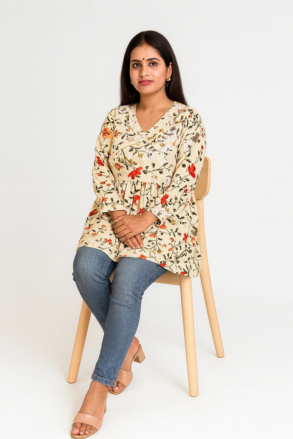 lucknowi chikankari Woman wearing a yellow floral dress sitting on a wooden chair against a white background