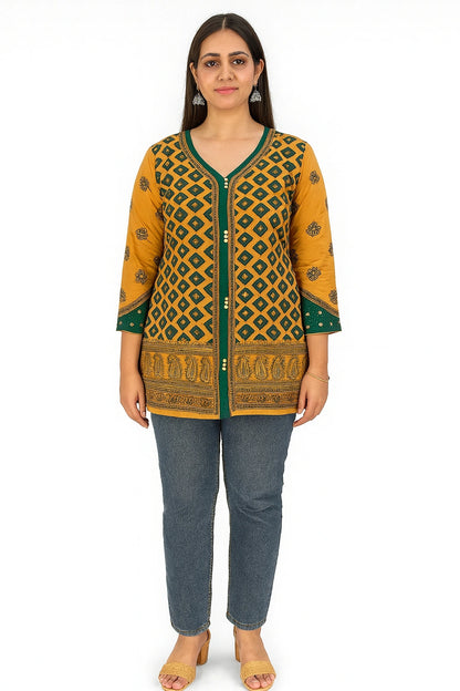 Woman wearing a lucknowi chikankari mustard yellow and green patterned top with blue jeans on a white background