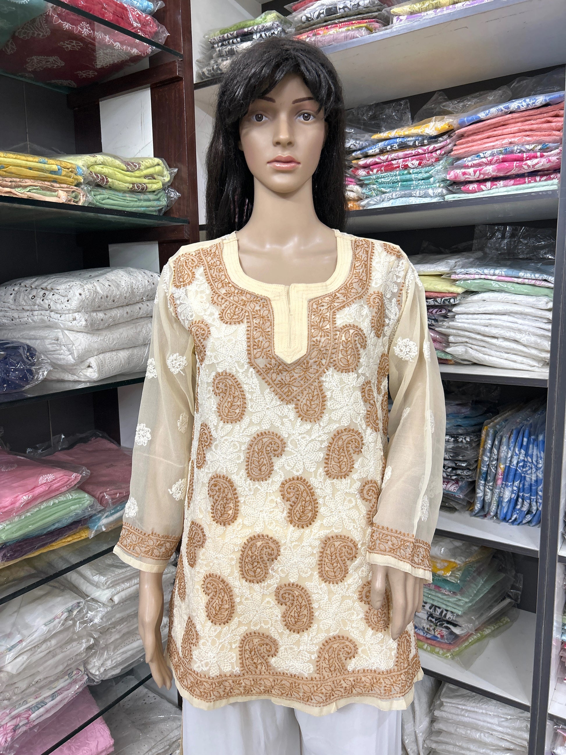 Mannequin wearing a lucknowi chikankari beige and brown patterned top in a fabric store.