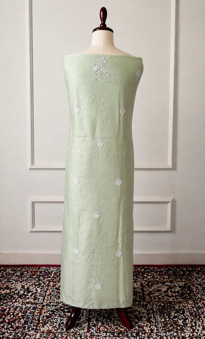 Light green dress with floral embroidery on a mannequin against a white paneled wall.