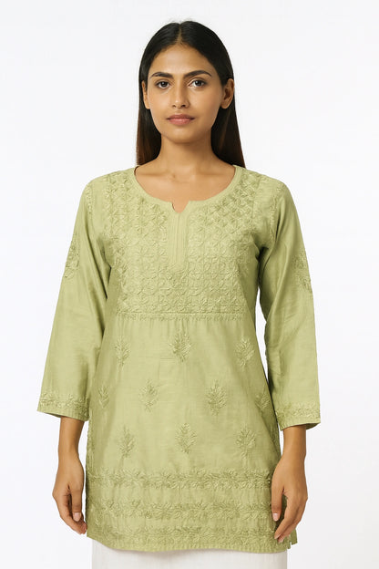 Woman wearing a light green embroidered kurta against a white background