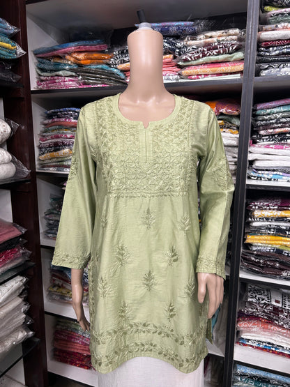 Mannequin wearing a green embroidered dress in a fabric store.