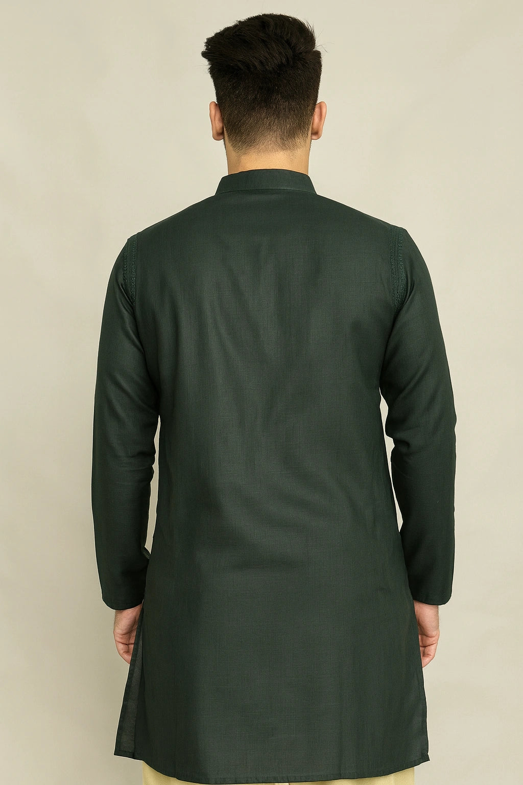 Man wearing a lucknowi chikankari dark green kurta against a beige background