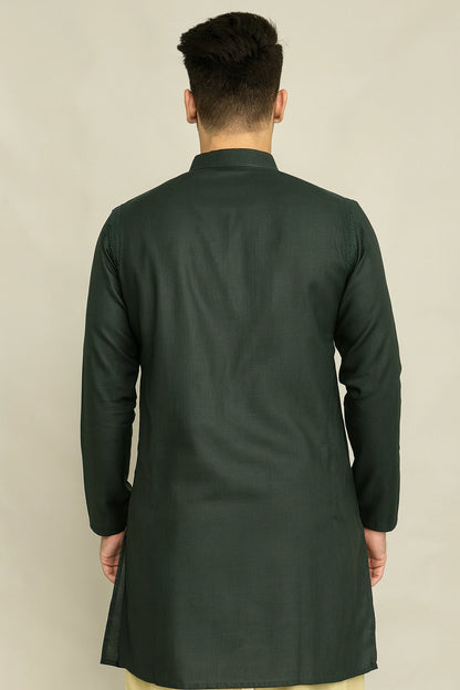 Man wearing a lucknowi chikankari dark green kurta against a beige background
