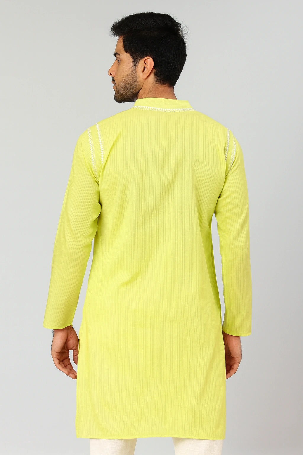 Man wearing a lucknowi chikankari light green kurta with white pants on a gray background