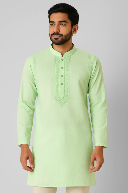 Man wearing a lucknowi chikankari light green kurta with white pants on a gray background