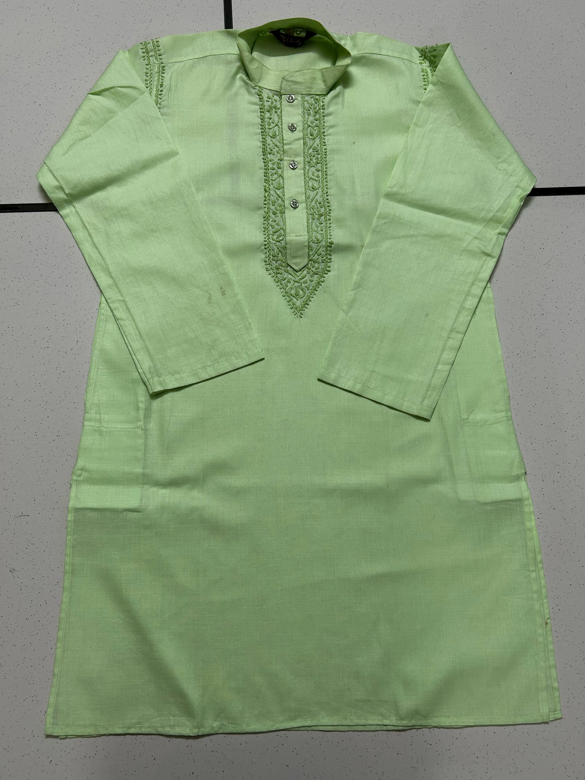 Green kurta with intricate embroidery on a gray background