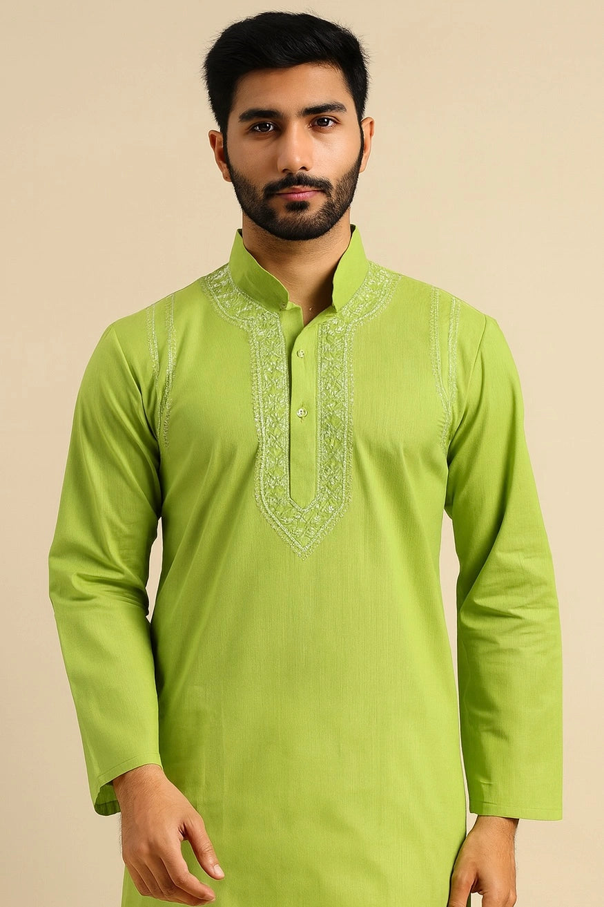 Man wearing a green kurta with intricate embroidery on a beige background
