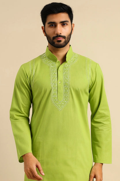 Man wearing a green kurta with intricate embroidery on a beige background
