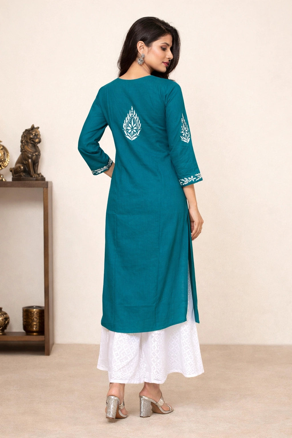 Woman wearing a teal kurta with white pants in a minimal setting