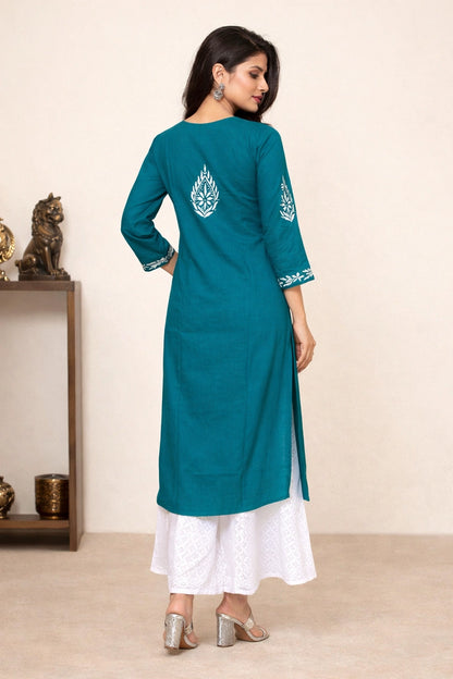 Woman wearing a teal kurta with white pants in a minimal setting