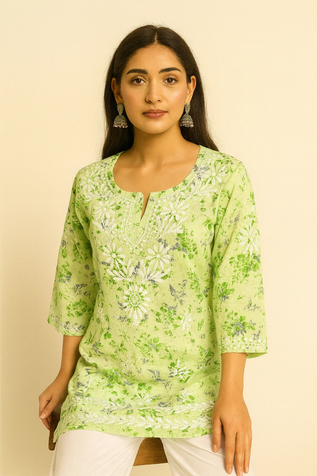 Woman wearing a lucknowi chikankari green floral top against a beige background
