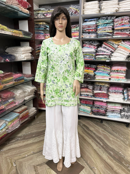 Mannequin wearing a lucknowi chikankari green floral top and white pants in a fabric store.