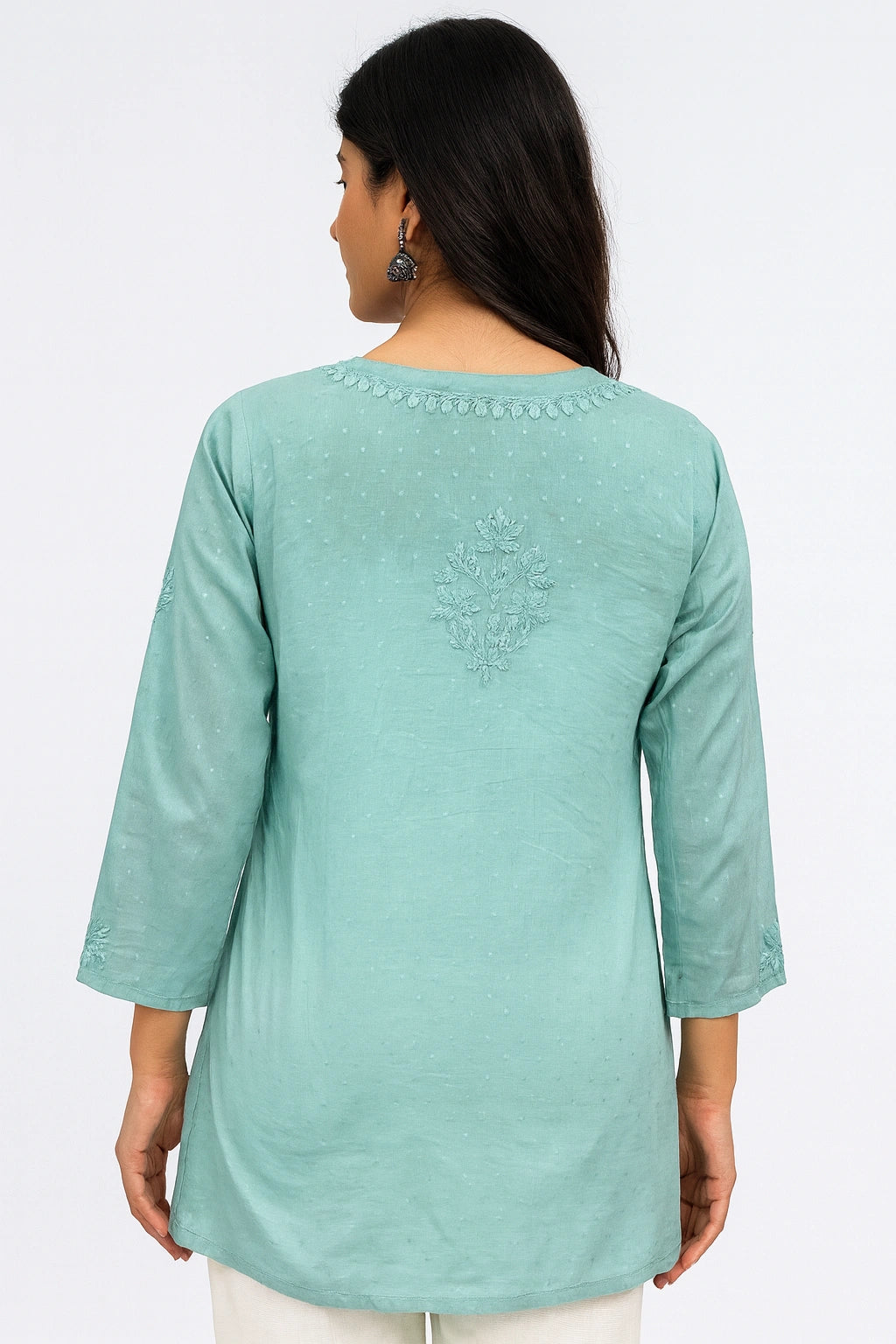 Woman wearing a light blue embroidered top on a white background