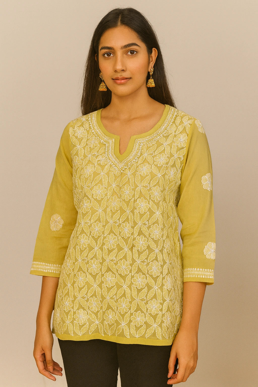 Woman wearing a lucknowi chikankari yellow patterned top against a beige background