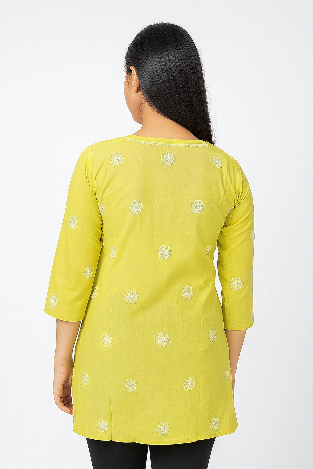 Woman wearing a lucknowi chikankari yellow kurta with white floral patterns on a white background