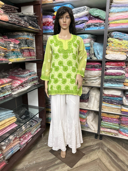 lucknowi chikankari Mannequin wearing a green patterned top and white pants in a fabric store.