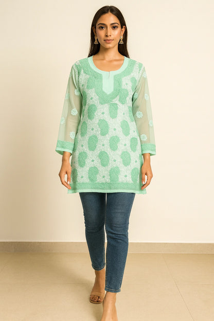 lucknowi chikankari Woman wearing a green patterned top and blue jeans against a beige background