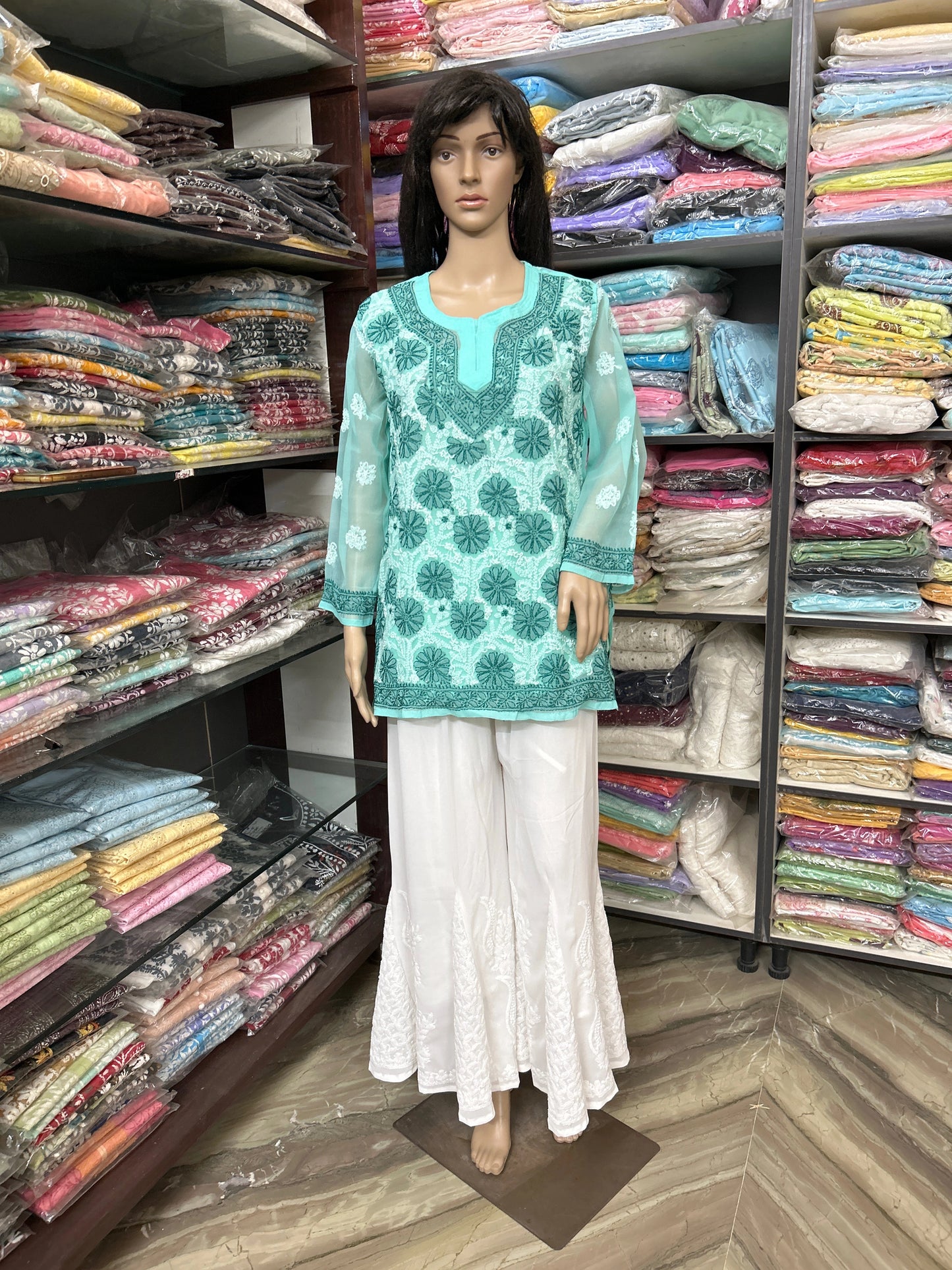 lucknowi chikankari Mannequin wearing a teal top and white pants in a fabric store