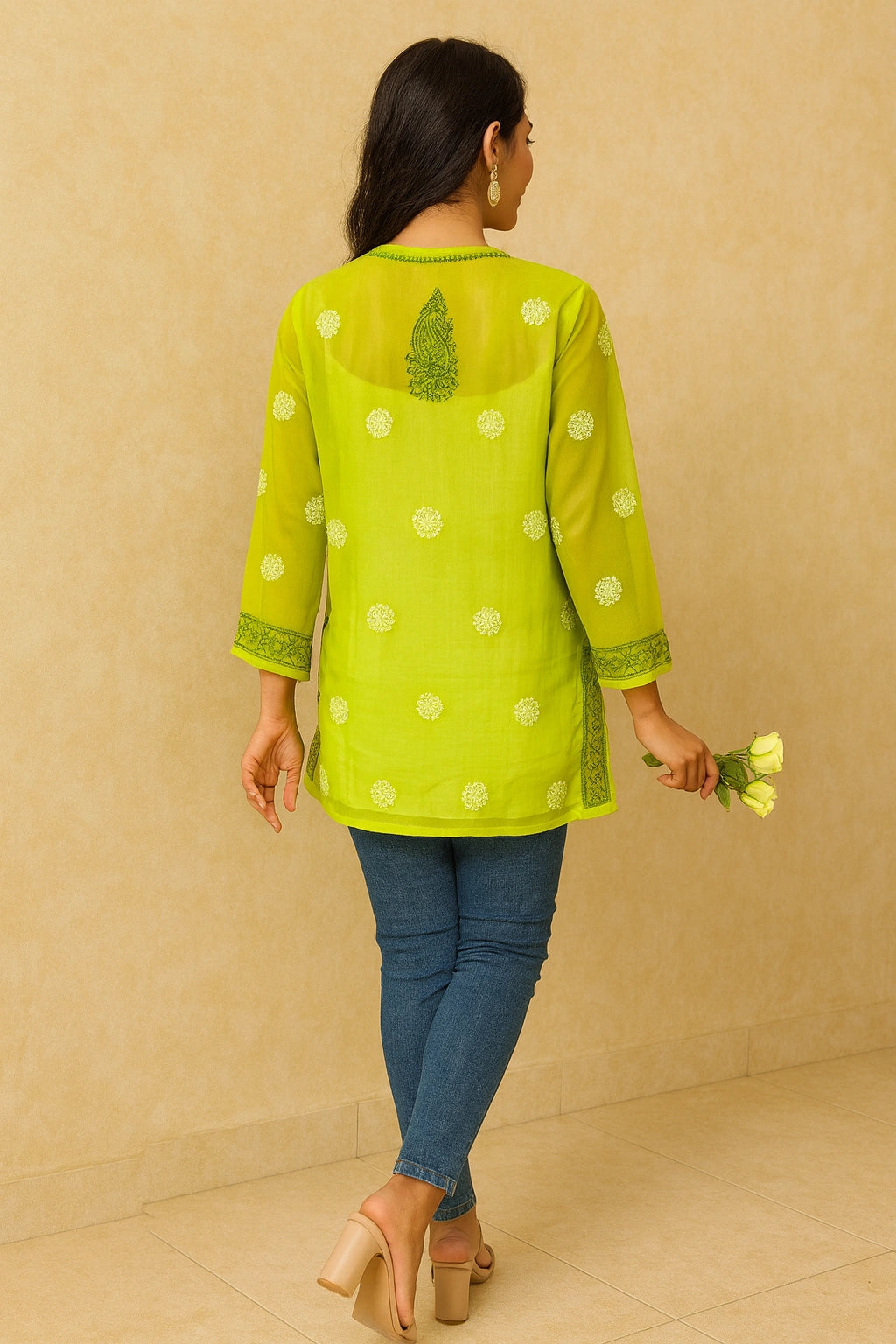 Woman wearing a green embroidered top with white polka dots on a gray background