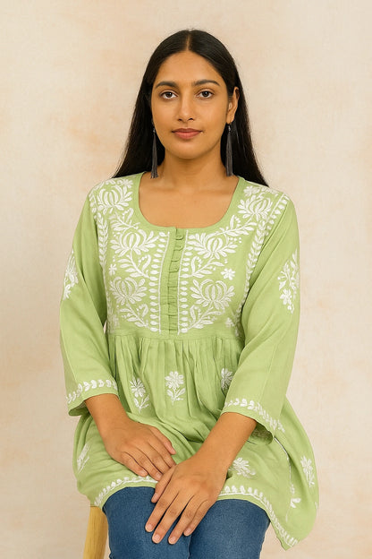 Woman wearing a green embroidered kurta on a beige background