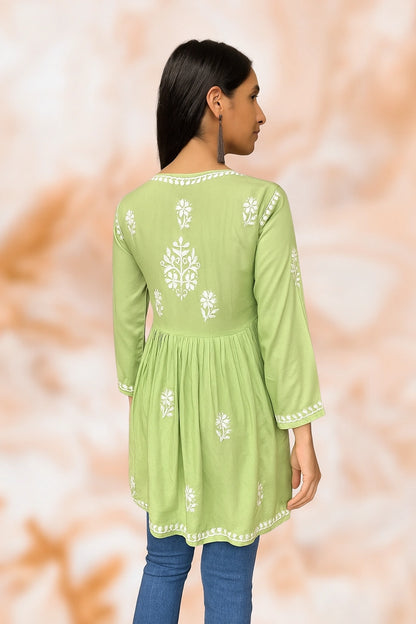 Person wearing a lucknowi chikankari light green top with a subtle pattern on a beige background