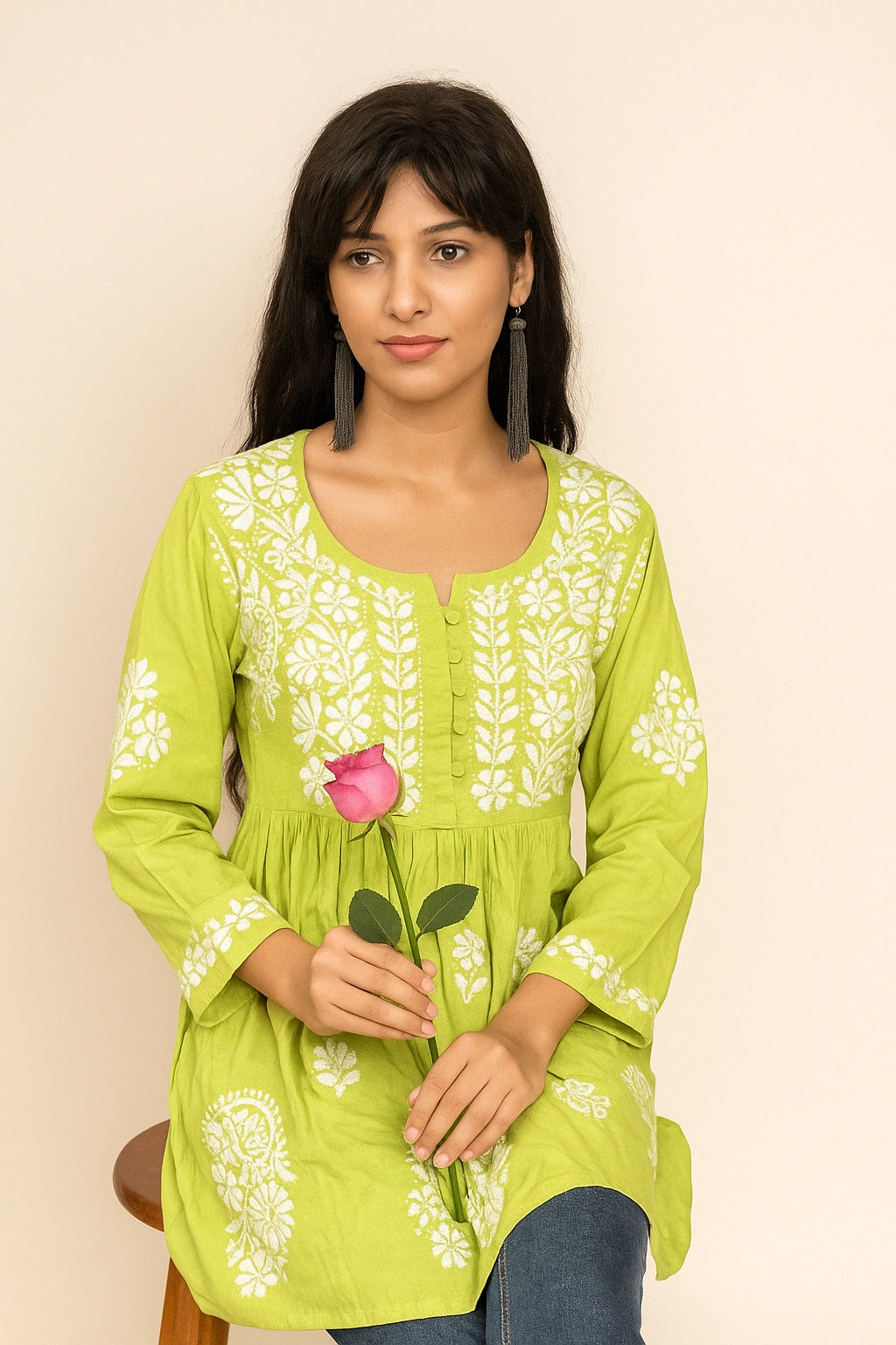 Woman wearing a green embroidered kurta on a beige background